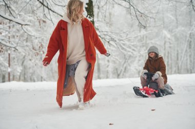 Kızağın üstünde. Anne ve kızı kış çayırlarında ve ormandalar..