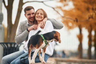 Gülümsüyor, eğleniyor. Hoş bir çift, sevimli köpekleri dışarıda..