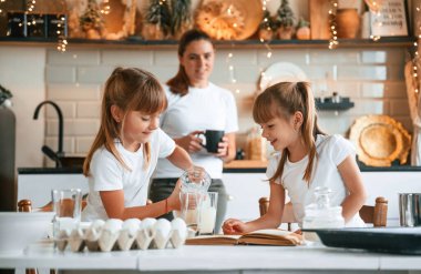 Yemek hazırlamayı öğreniyorum. Anne ve iki küçük kızı mutfakta çelenklerle birlikte..