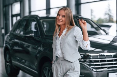 Yeni otomobilin anahtarları. Resmi kıyafetli kadın araba galerisinde..