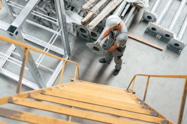 Merdivene tırmanmak gibi. Gri üniformalı genç fabrika işçisi.