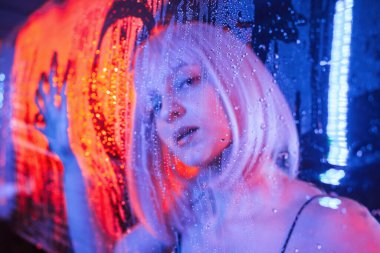 Aşk kalbi yüzeyde şekillenir. Beyaz saçlı şık kadın ıslak şeffaf plastik çarşafın arkasında..