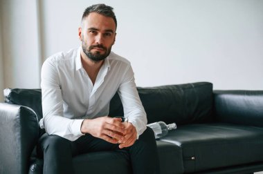 Kanepede oturuyor. Alkolik genç adam içeride..