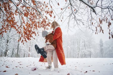 Oynamak ve eğlenmek. Anne ve kızı kış çayırlarında ve ormandalar..