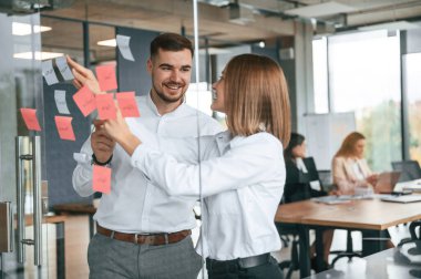 Cama iki kişi etiket yapıştırıyor. Projeyi planlıyorum. Bir grup ofis çalışanı içeride birlikte..