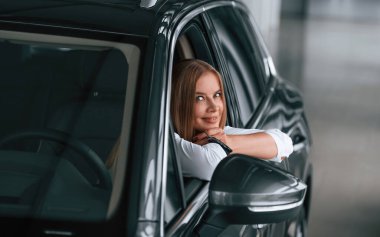 Açılmış pencereden bakıyorum. Kadın arabada oturuyor ve onu sürüyor..