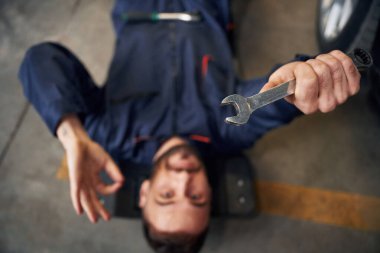 Aletle yere yat. Araba tamircisi otomobille garajda..