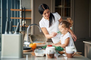 Lavabonun yanında. Anne ve kızı mutfakta yemek hazırlıyorlar..
