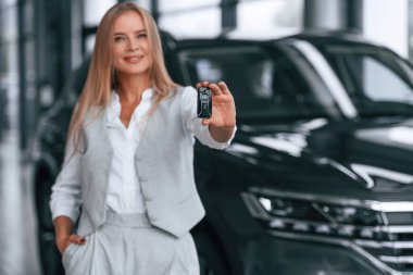 Anahtarları tutuyorum. Resmi kıyafetli kadın araba galerisinde..