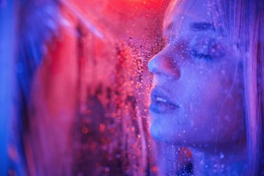 Şehvetli görünüş. Beyaz saçlı şık kadın ıslak şeffaf plastik çarşafın arkasında..