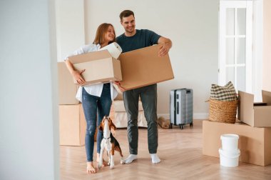 Kutularla ileri doğru yürüyorlar. Köpekli genç çift yeni evine taşınıyor..