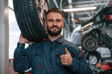 Yepyeni bir lastikle. Araba tamircisi otomobille garajda..