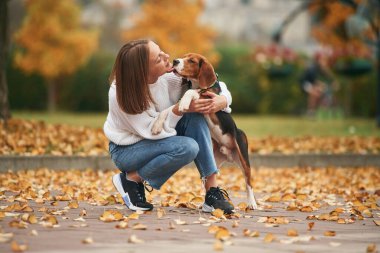 Yan görünüş, evcil hayvanla oynamak. Genç kadın köpeğiyle birlikte parkta..
