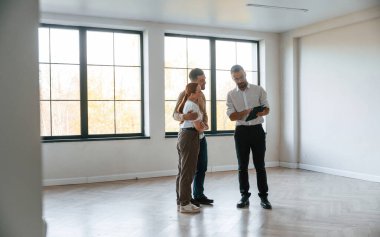 Boş oda. Emlakçı genç bir çifte bir daire gösteriyor..