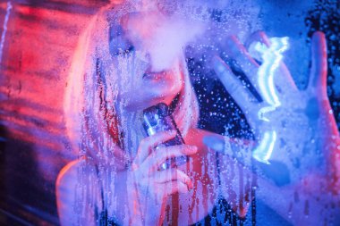 Buharlaştırma, tutma cihazı. Beyaz saçlı şık kadın ıslak şeffaf plastik çarşafın arkasında..