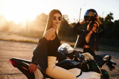 Arka planda duman. Motosikletli iki kadın dışarıda birlikteler..
