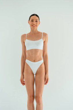 Ön manzara. Zayıf vücutlu genç bir kadın stüdyoda spor kıyafetleri giyiyor..