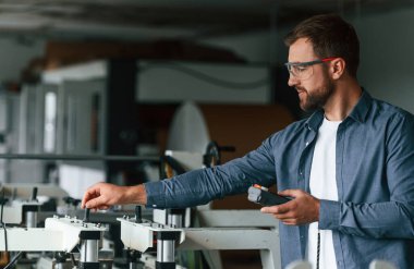 Makineyle çalışmak. Yakışıklı adam ekolojik kutular üreten fabrikada..