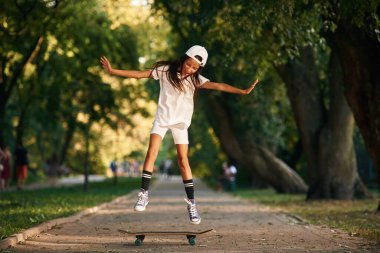 Numara yapıyor, eğleniyor. Dışarıda kaykaylı mutlu küçük kız.