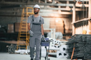 Ön manzara, ileri yürüme. Gri üniformalı genç fabrika işçisi.