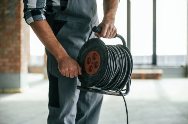 Kabloları tutuyorum. Tamamlanmamış binanın içerisindeki tamircinin yakın görüntüsü.