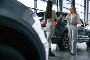 Anahtarları veriyorum. Kadın müdür kadın müşteriye araba galerisinde yardım ediyor..