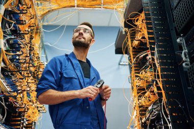 Yakışıklı genç adam sunucu odasında internet cihazları ve kablolarla çalışıyor..