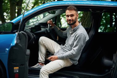 Güzel genç adam dışarıda mavi arabada oturuyor..