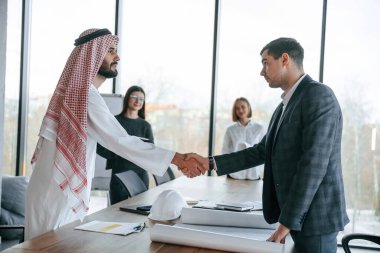 Tokalaşıyorum. Geleneksel kıyafetli Müslüman işadamı ve görevde meslektaşları.