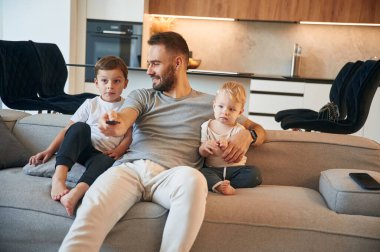 Rahatlama kavramı. İki erkek çocuğu olan baba kanepede oturuyor..