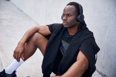 Kulaklıkla. Yakışıklı siyah adam gündüz vakti dışarıda poz veriyor..