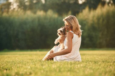 Güzel bir kadın, sevimli köpeğiyle birlikte sahada..