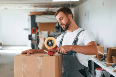Ürünü paketliyorum. Yakışıklı adam ekolojik kutular üreten fabrikada çalışıyor..