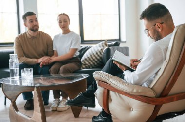 Adam notlar yazıyor. Psikolog randevusundaki çift..