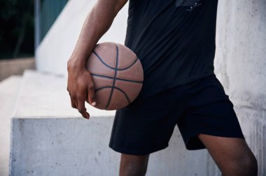 Manzarayı kapat. Genç siyah adam basketbol topuyla dışarıda..