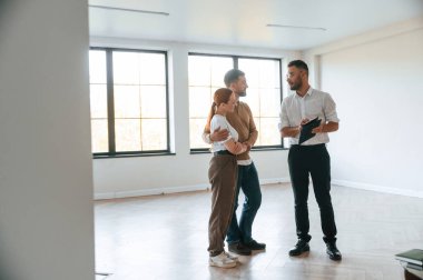 Boş oda. Emlakçı genç bir çifte bir daire gösteriyor..