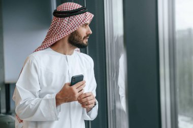 Ofiste, telefonla. Geleneksel kıyafetli başarılı Müslüman iş adamı.