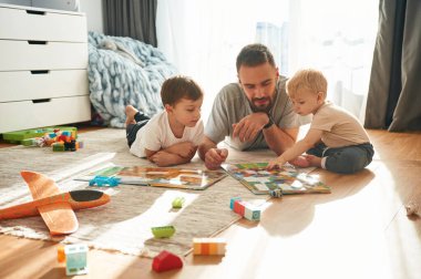 Masa oyununun tadını çıkarıyorum. Babam yerde oyuncaklarla oynayan iki küçük çocukla oynuyor..
