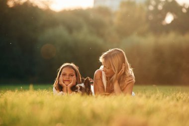 Çimlere uzanmak. Anne kızıyla ve sevimli köpeğiyle açık arazide..