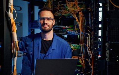 Kameraya bakıyorum. Genç adam sunucu odasında internet ekipmanı ve kablolarıyla çalışıyor..