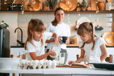 Yemek hazırlamayı öğreniyorum. Anne ve iki küçük kızı mutfakta çelenklerle birlikte..