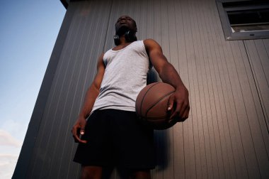 Metal yüzey binasının karşısında duruyor. Genç siyah adam basketbol topuyla dışarıda..