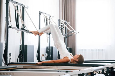 Uzan ve bacaklarını aç. Spor salonundaki genç kadın egzersiz yapıyor..