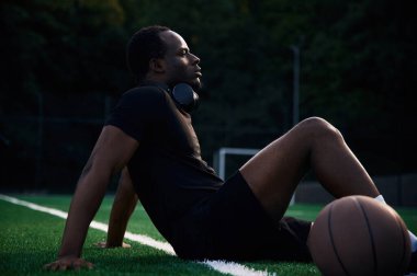 Oturup dinleniyorum. Genç siyah adam basketbol topuyla dışarıda..