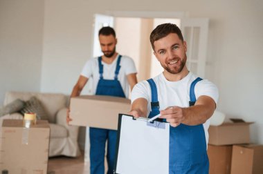 Belgeleri imzalayın. Bir odada hareket eden iki servis çalışanı.