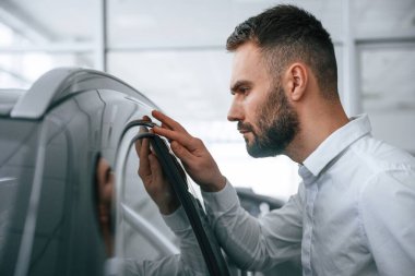 Cilalı yüzeye bakıyorum. Resmi giyinen işçi oto kuaföründe..