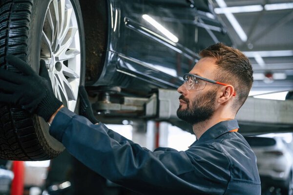Ремонт сломанной машины. Авторемонтник в гараже с автомобилем.