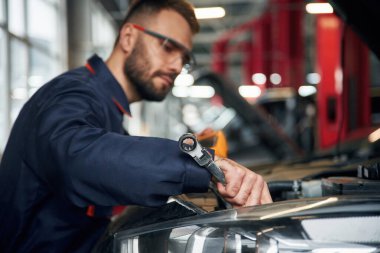 Profesyonel elektro aygıt ellerinde. Araba tamircisi otomobille garajda..