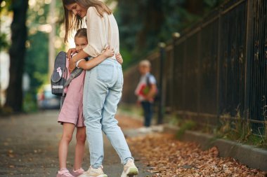 Çocuk arka planda duruyor. İki çocuklu bir kadın okula gidiyor, eğitim anlayışı..