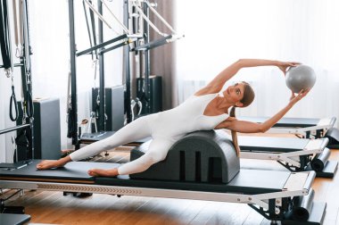 Topu elinde tutuyor. Spor salonundaki genç kadın egzersiz yapıyor..